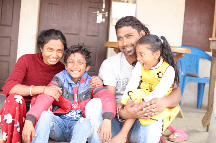 Smiling family in front of their home