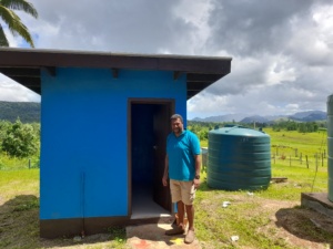 A man stands outside a newly constructed WASH facility, which can be used for Menstrual Hygiene at the Nalaba School.