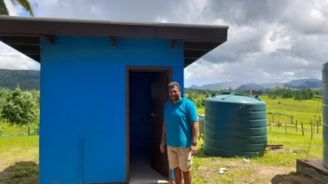 A man stands outside a newly constructed WASH facility, which can be used for Menstrual Hygiene at the Nalaba School.