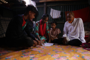 A family sit together on the floor in an informal settlement in Dhaka, Bangladesh