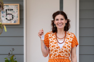 Celeste stands in front of her new home holding the doorkey.