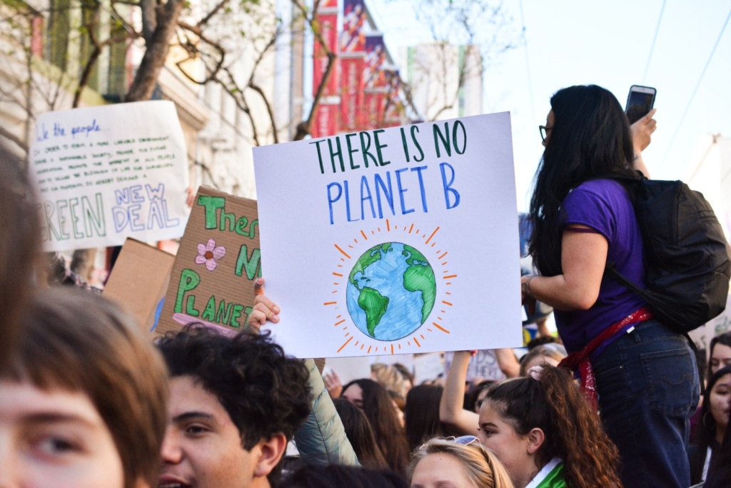 Young People rally for Climate Change at a Global Climate Strike Event. Someone holds a sign reading 'There is No Planet B' with a drawing of earth.