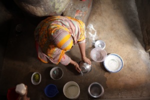 image is taken from a birds eye perspective. A woman sits on the floor surrounded by bowls.