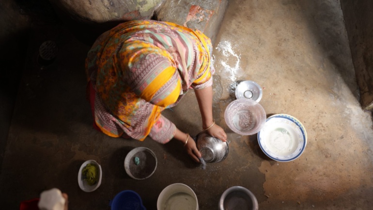 image is taken from a birds eye perspective. A woman sits on the floor surrounded by bowls.