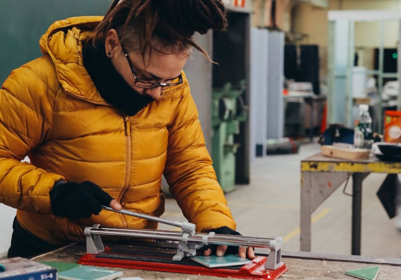 Elizabeth learning to cut tiles in the Habitat Women workshop